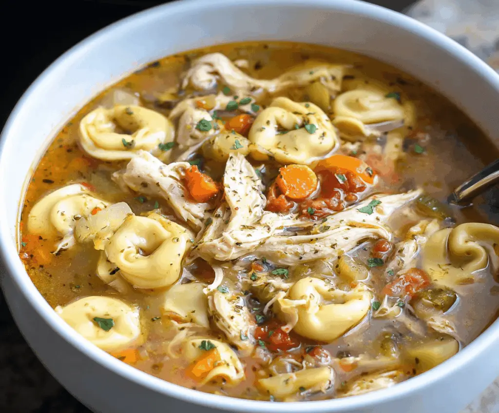 Creamy Crockpot Chicken Tortellini Soup with vegetables and herbs in a bowl