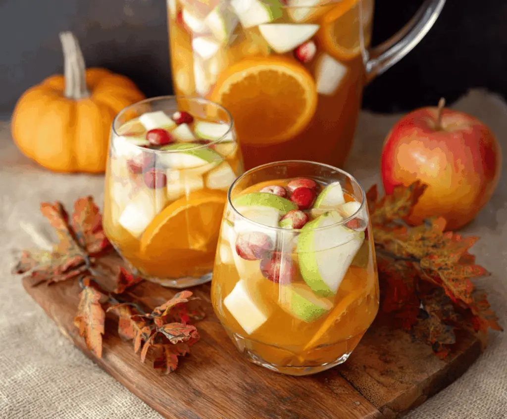 A refreshing glass of Pumpkin Spice Sangria filled with citrus slices, apple chunks, and garnished with cinnamon, perfect for autumn celebrations.